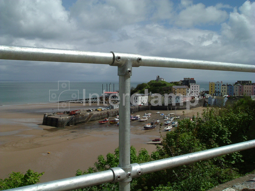 View of an Interclamp tube clamp handrail installed on a beachfront promenade in a seaside town, offering support to beachgoers with the horizon in view.